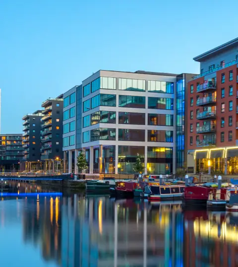 Leeds: edifici moderni riflessi in un canale all’imbrunire