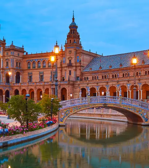 Siviglia: una grande piazza monumentale con ponte e canale al tramonto