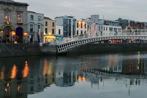 Dublino: l’Ha’penny Bridge sul fiume Liffey all’imbrunire, con i palazzi colorati del lungofiume riflessi nell’acqua