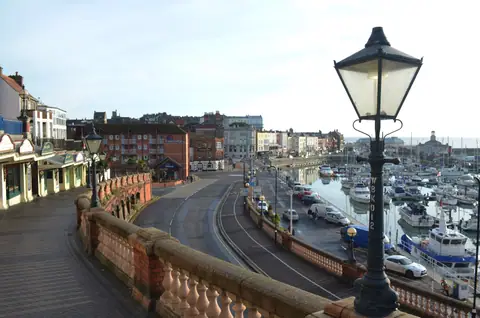Ramsgate: il lungomare di Royal Parade con un lampione in primo piano, il porto turistico pieno di barche e la città sullo sfondo