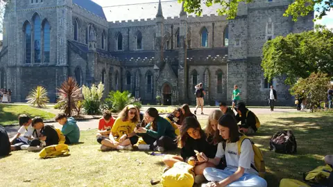 Ragazzi seduti sul prato davanti a una cattedrale gotica