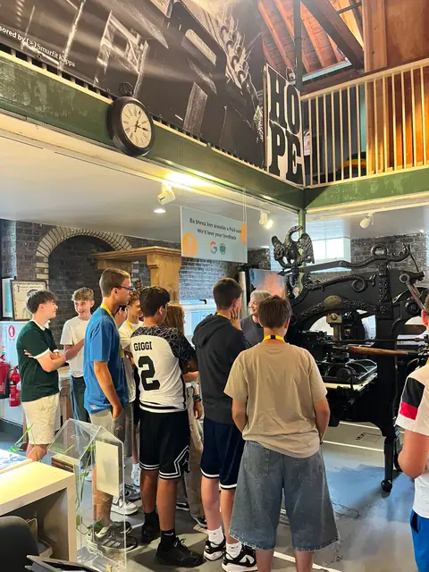 Ragazzi osservano un’antica macchina da stampa durante la visita a un museo