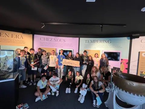 Foto di gruppo in una sala espositiva dedicata al cioccolato, con pannelli illustrati alle pareti