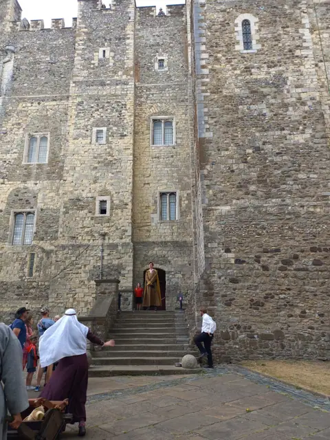 Ingresso di un castello medievale in pietra con figuranti in costume d’epoca