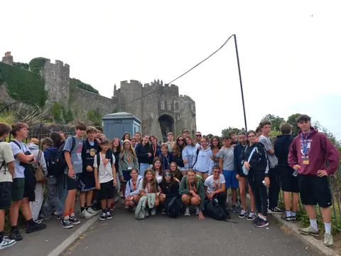 Foto di gruppo lungo una strada, con le mura di un castello sullo sfondo