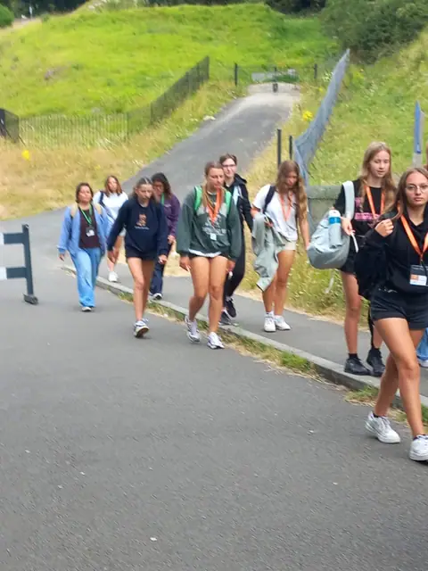 Ragazze con il cordino del gruppo salgono lungo un sentiero su una collina verde