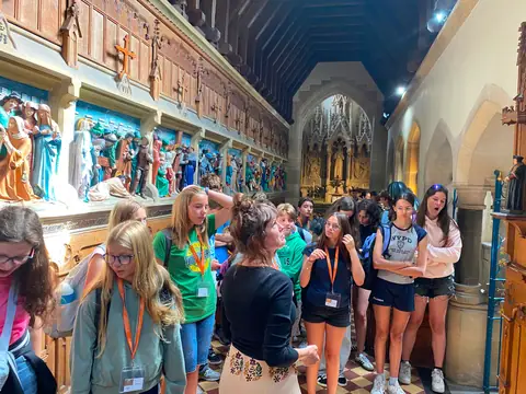 Ragazzi ascoltano una guida all’interno di una chiesa decorata da rilievi scolpiti e dipinti