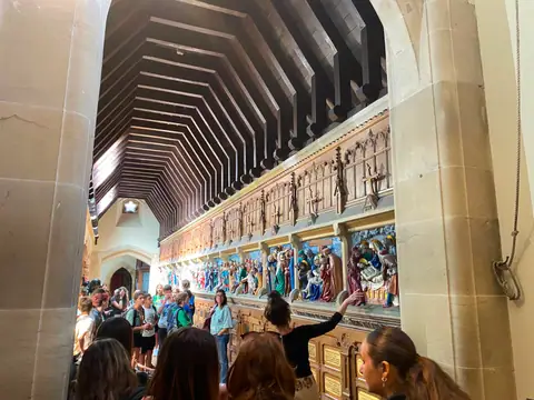 Gruppo in visita a una chiesa con soffitto in legno e pareti decorate da rilievi colorati
