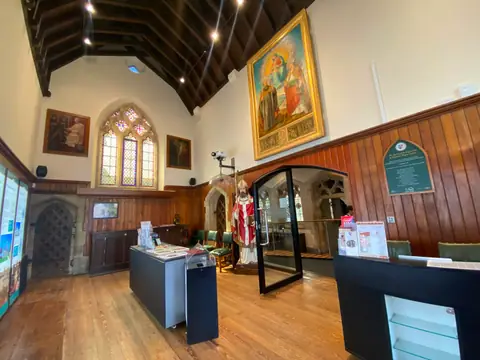 Sala d’ingresso dello Shrine of St Augustine & National Pugin Centre, con pareti in legno, una vetrata e un grande dipinto sacro
